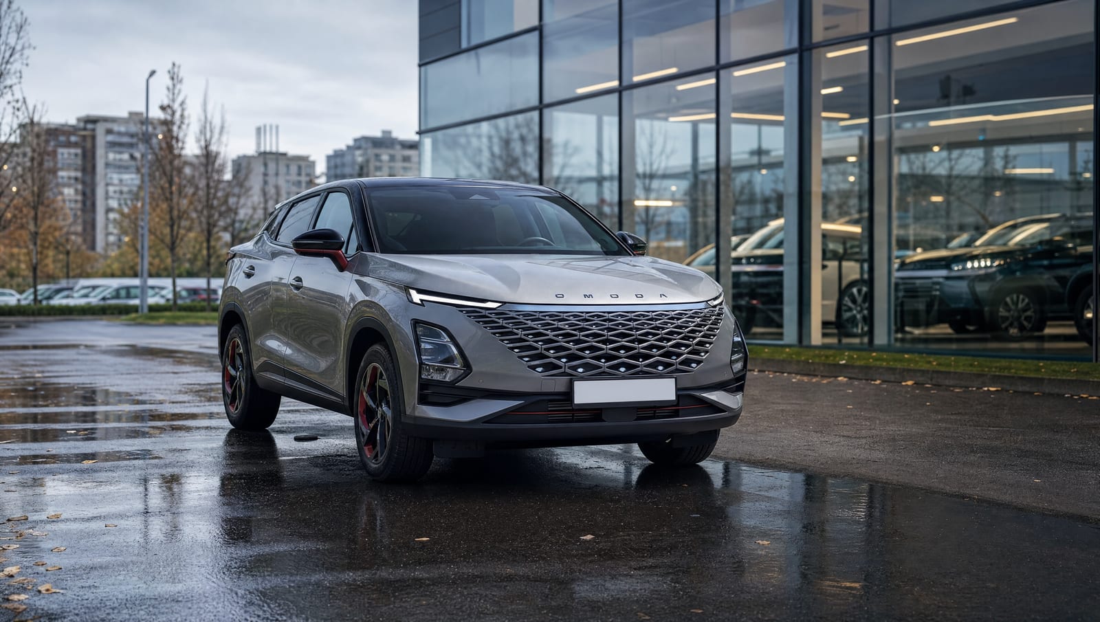 SUV Omoda gri parcat pe asfalt ud în fața unui showroom de sticlă, cu blocuri de locuințe în fundal