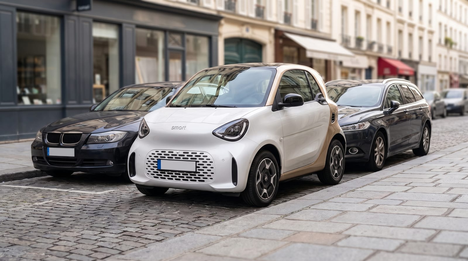 Smart #2, electrică urbană foarte scurtă în două tonuri, cu acoperiș crem, parcată între două mașini mult mai lungi pe o stradă europeană pietruită
