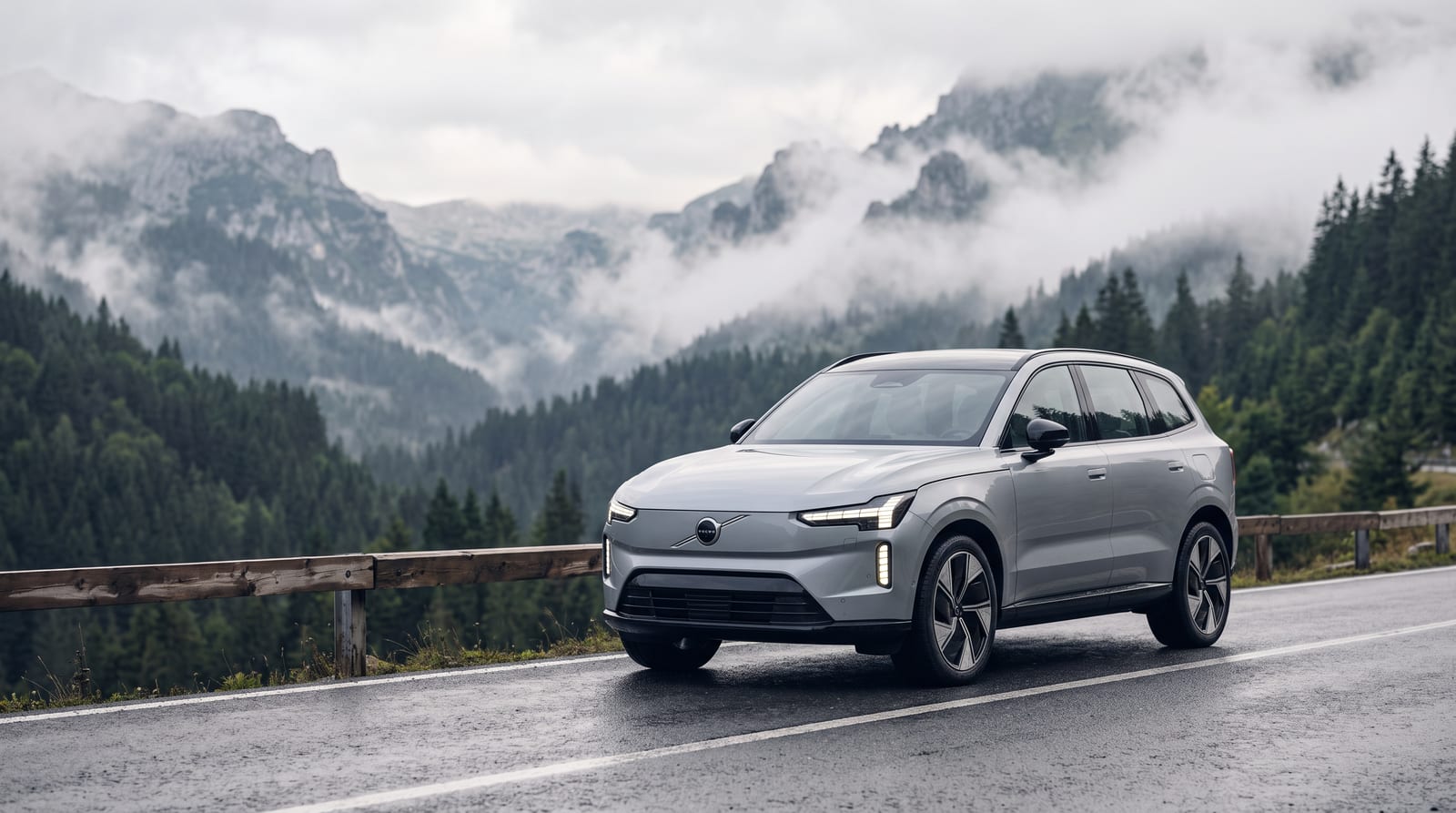 SUV electric Volvo EX60 gri, parcat pe marginea unui drum de munte din Carpați, în lumină rece de dimineață, cu vârfuri învăluite în ceață în fundal